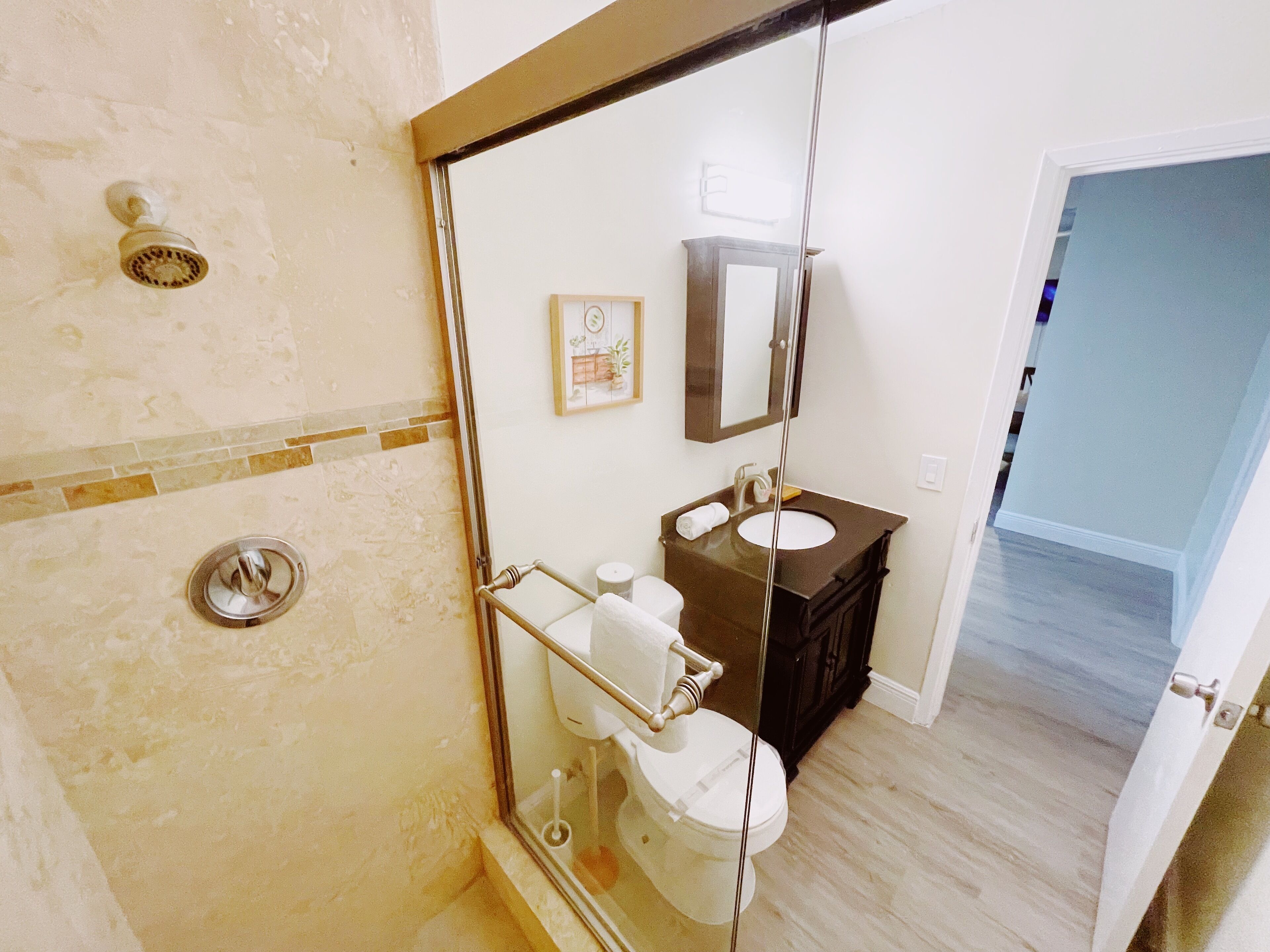 Une salle de bain avec une douche à parois de verre, des toilettes, un lavabo et un miroir.