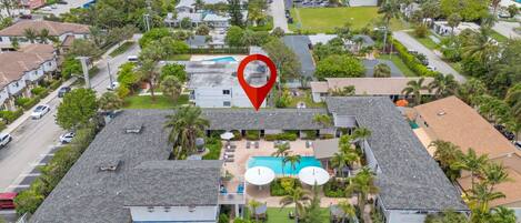 A hotel with a swimming pool, multiple parking spaces, and a view of the surrounding neighborhood.