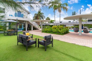 A resort with outdoor seating, a pool, and a covered area with stairs leading to a building. - Sea Steps by Lowkl (Pompano Beach)