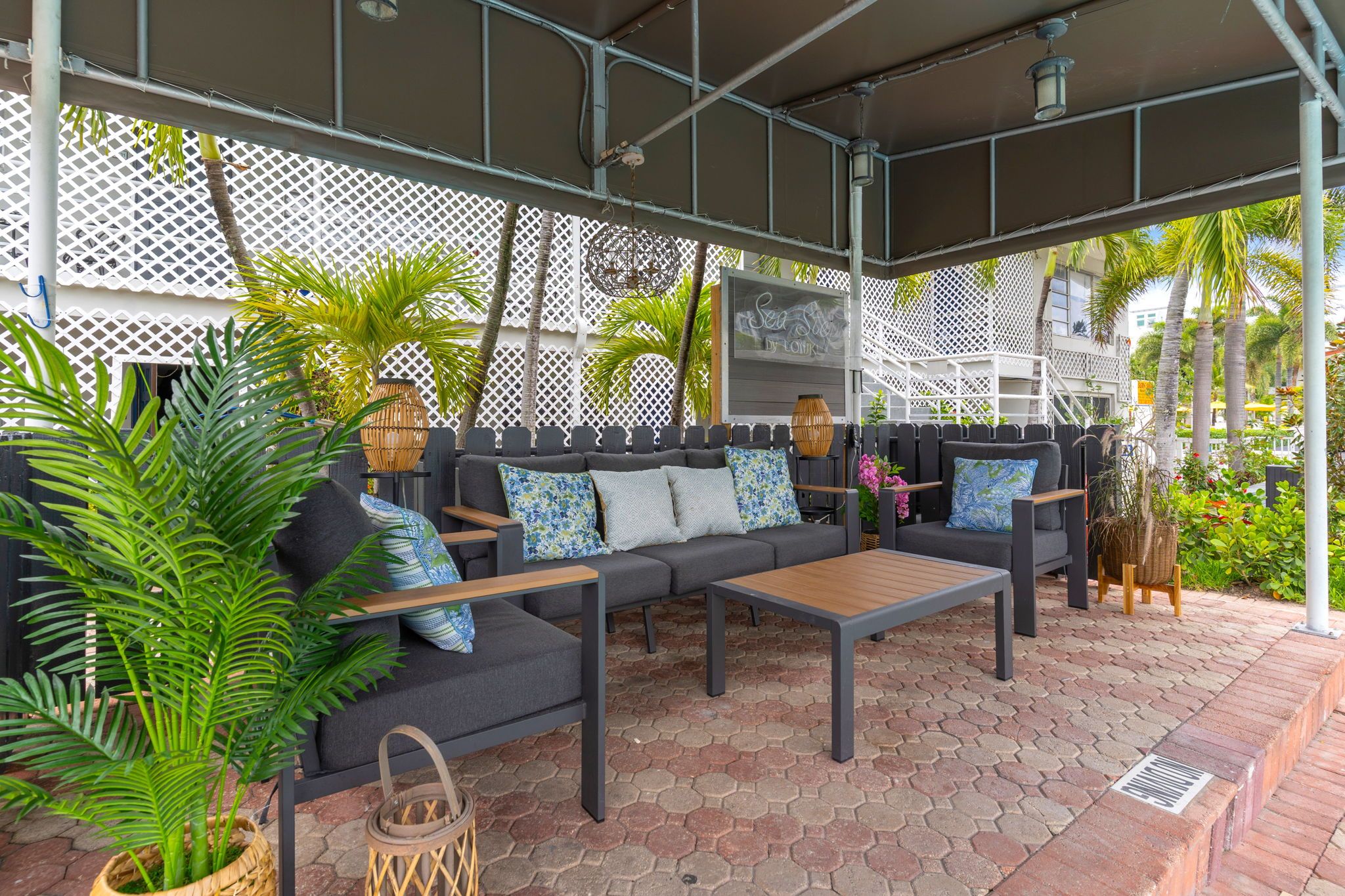 An outdoor seating area with a sofa, table, and potted plants.