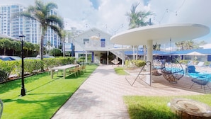A resort courtyard with a pool, outdoor seating, and a large white gazebo. - Sea Steps by Lowkl (Pompano Beach)