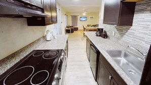 A modern kitchen with a stove, sink, and a dining area in the background. - Sea Steps by Lowkl (Pompano Beach)