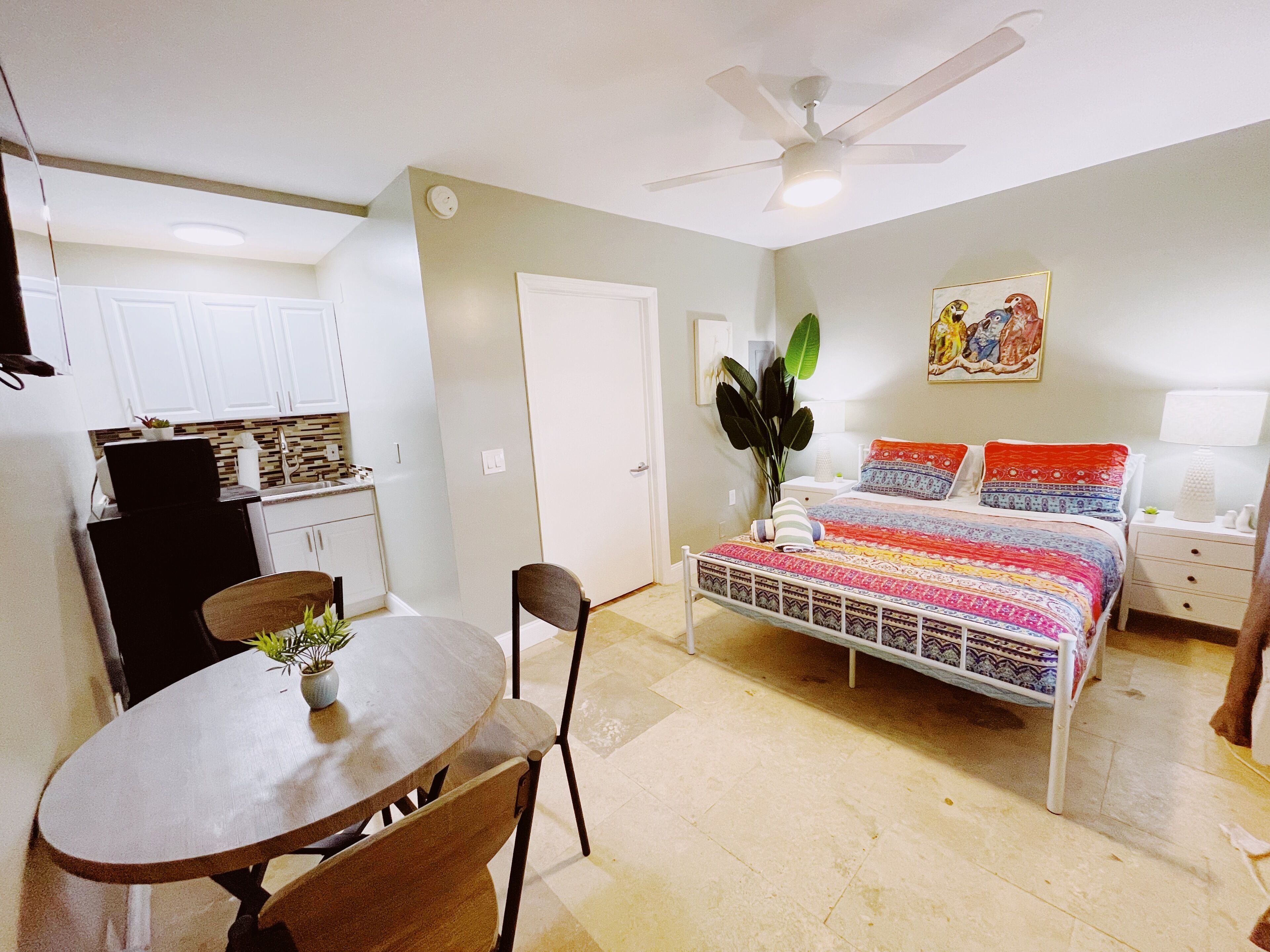 Quarto compacto com cama, mesa de cabeceira e ventilador de teto.