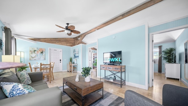 A modern living room with a wooden ceiling, a TV, and a dining area. - Sea Steps by Lowkl (Pompano Beach)