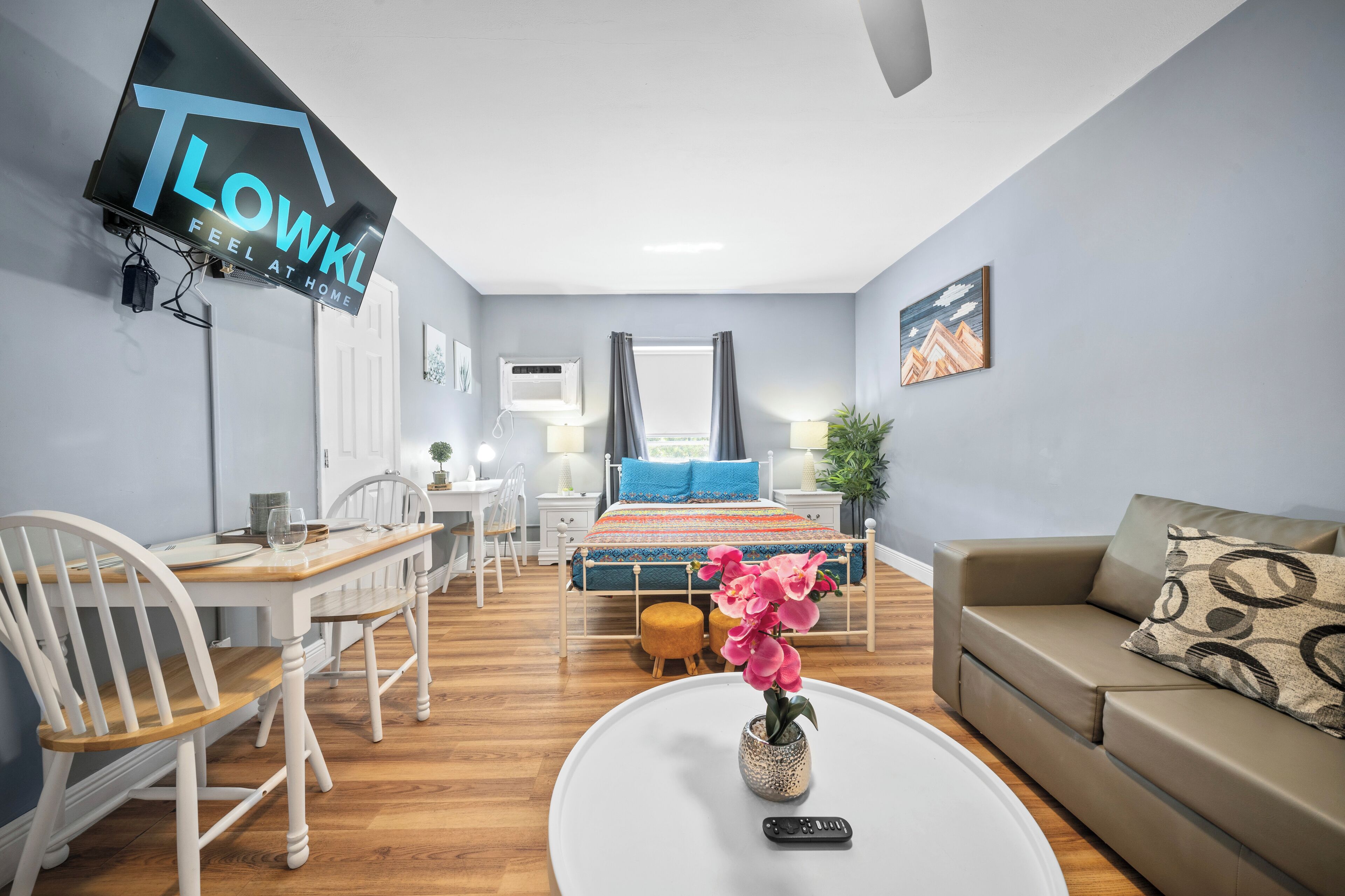 Ein modernes Hotelzimmer mit Bett, Sofa, Esstisch und Fernseher.