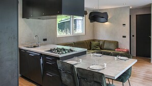 A modern kitchen with a central island, built-in appliances, and a dining area with a table and chairs. - Pet friendly home in Epe with WiFi (Epe)