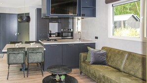 A compact kitchen with dark cabinets, a central island, and a dining area with two chairs. - Pet friendly home in Epe with WiFi (Epe)