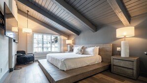 A bedroom with a large bed, wooden headboard, and a nightstand with a lamp. - Luxury 2-level Alpine Abode w/ hot tub + sauna access, very close to Gondola One (Vail)