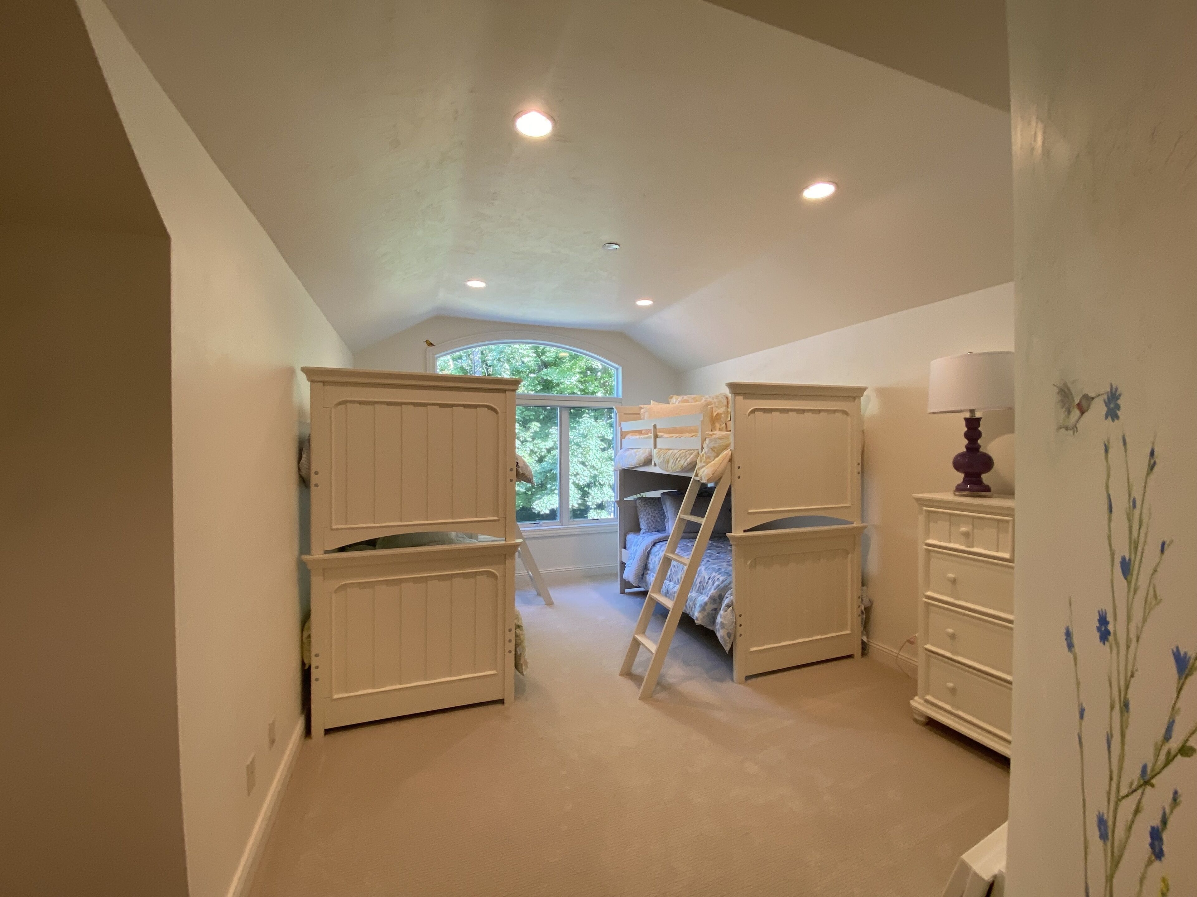 A bedroom with bunk beds, a ladder, and a dresser.