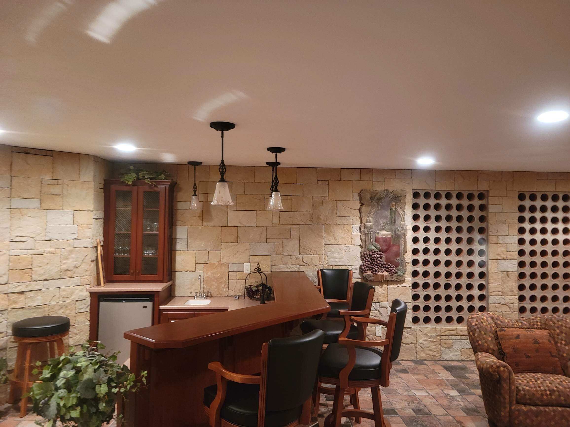 Un área de bar acogedora con paredes de piedra, una barra de madera y sillas de cuero negro.