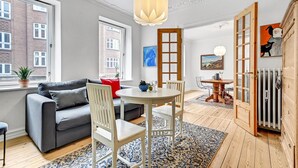 A modern living room with a grey sofa, white chairs, a round dining table, and a patterned rug. - 1 bedroom cozy apartment in Aarhus C (Aarhus C)