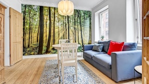 A living room with a forest mural, a white table, and a grey sofa with red cushions. - 1 bedroom cozy apartment in Aarhus C (Aarhus C)