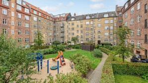 A courtyard with a playground, a brick building, and a pathway. - 1 bedroom cozy apartment in Aarhus C (Aarhus C)
