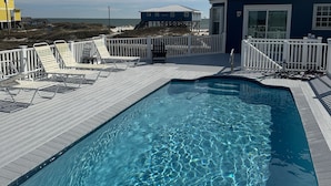 A swimming pool with a wooden deck, white railings, and a view of the ocean and beach houses in the background. - Awesome views of the Gulf, Easy walk to the beach and Private  Pool! (Gulf Shores)