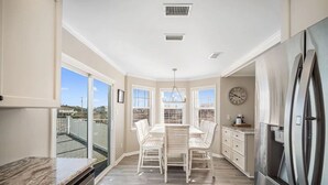 A modern kitchen with a dining area, large windows, and a view of the outdoors. - Awesome views of the Gulf, Easy walk to the beach and Private  Pool! (Gulf Shores)