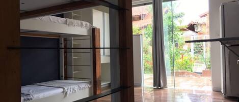 Una habitación con literas, una puerta de cristal que da a un balcón y un refrigerador.