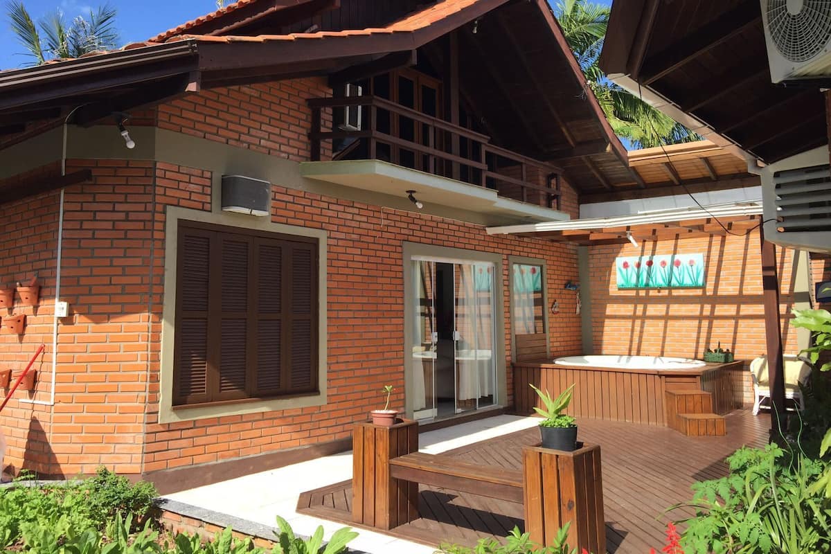 A two-story brick building with a balcony, a hot tub, and a wooden deck.