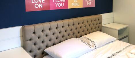A hotel room with a bed, a tufted headboard, and a wall with four motivational posters.