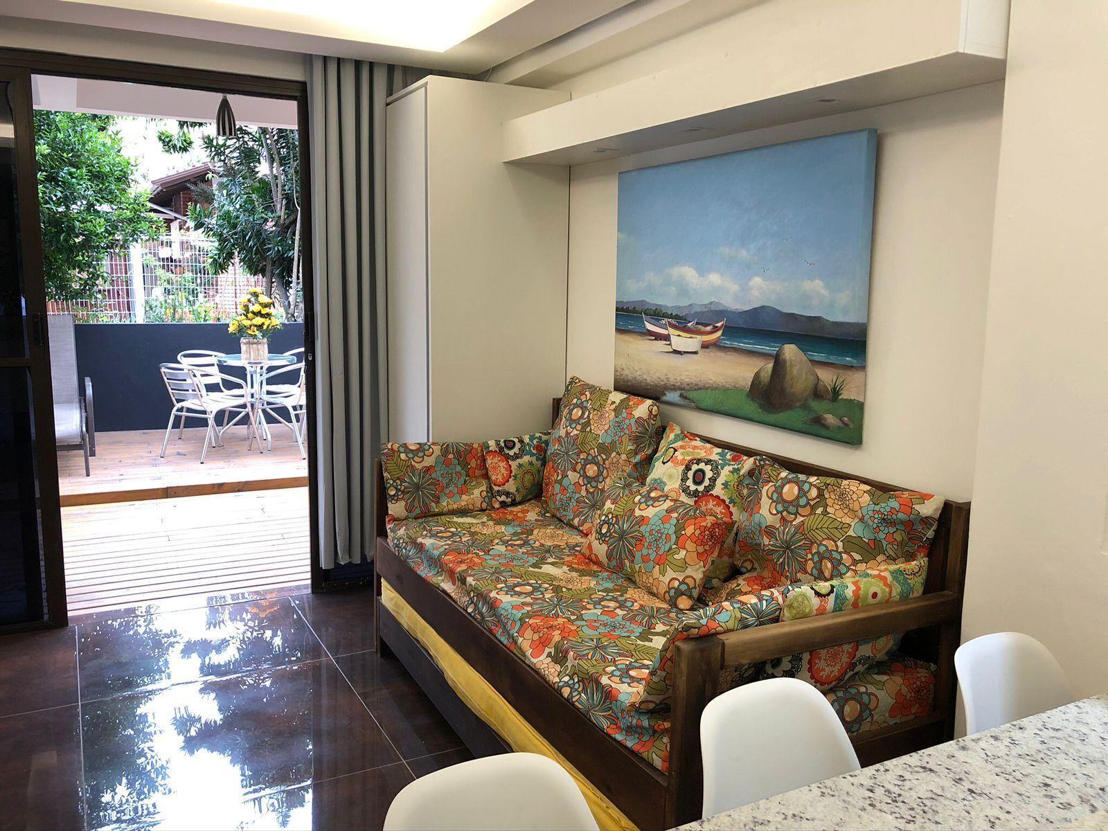 Un salón con sofá, un cuadro de una playa y una mesa de comedor.