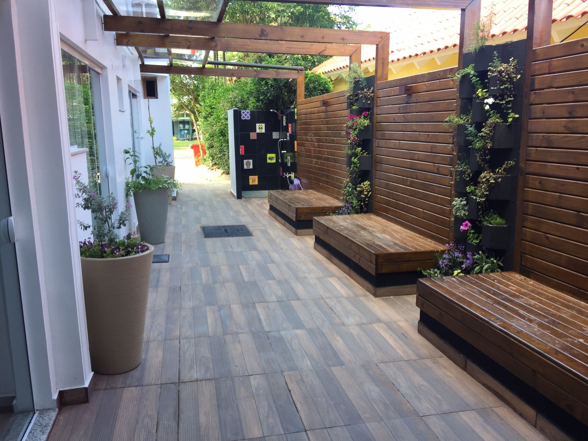 A covered outdoor area with wooden benches and planters.