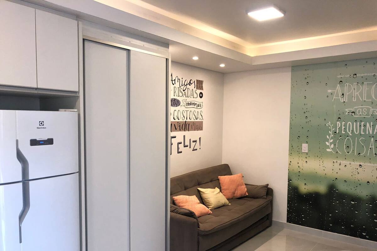 A modern kitchen with a white refrigerator, a brown sofa with cushions, and a wall with motivational quotes.