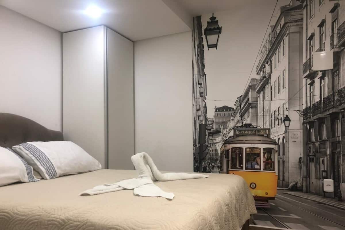 A hotel room with a bed, a trolley, and a city street view.