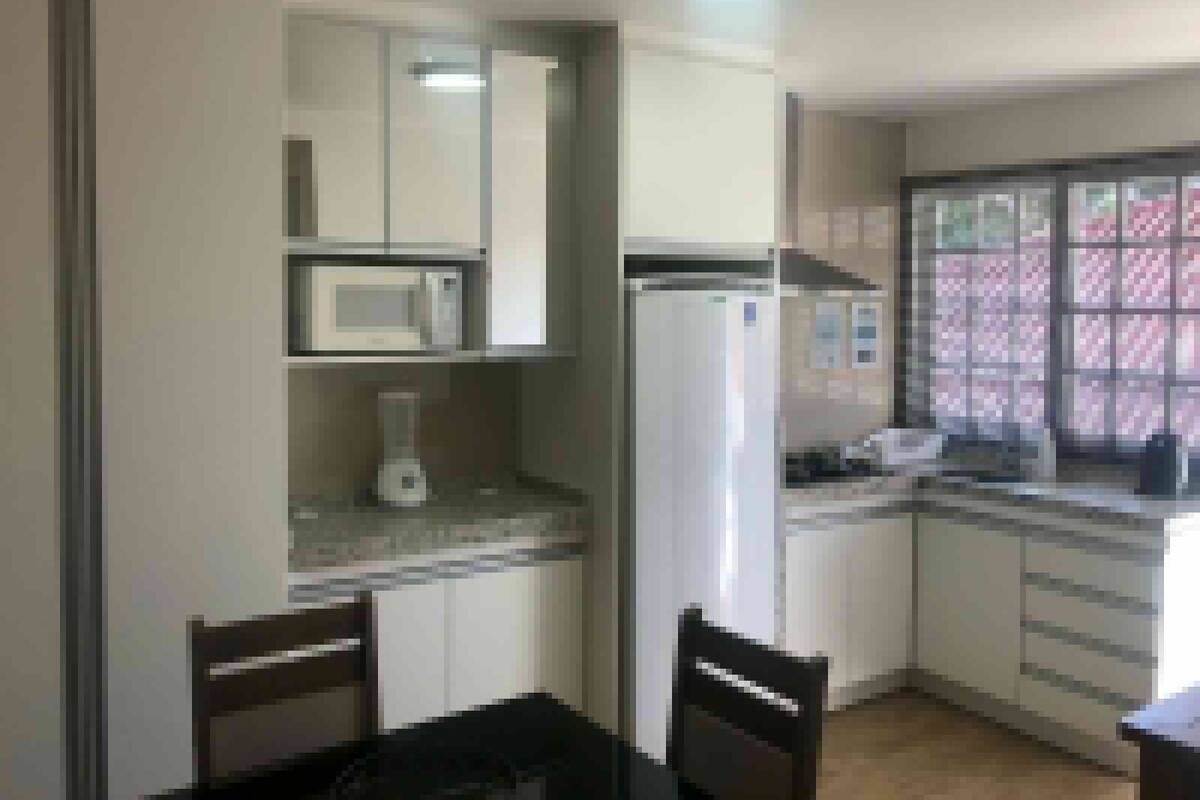 A compact kitchen with white cabinets, a microwave, a refrigerator, and a window with a view.