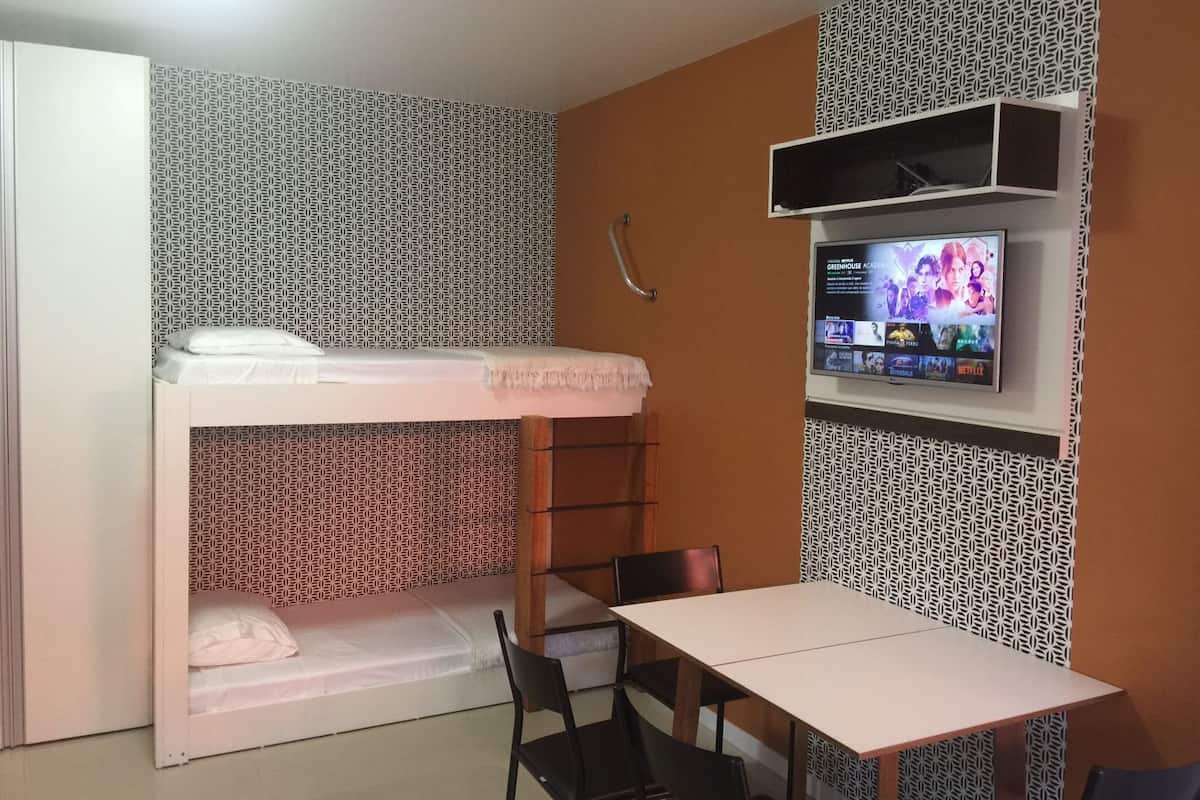 A bunk bed with a TV mounted on the wall above it.