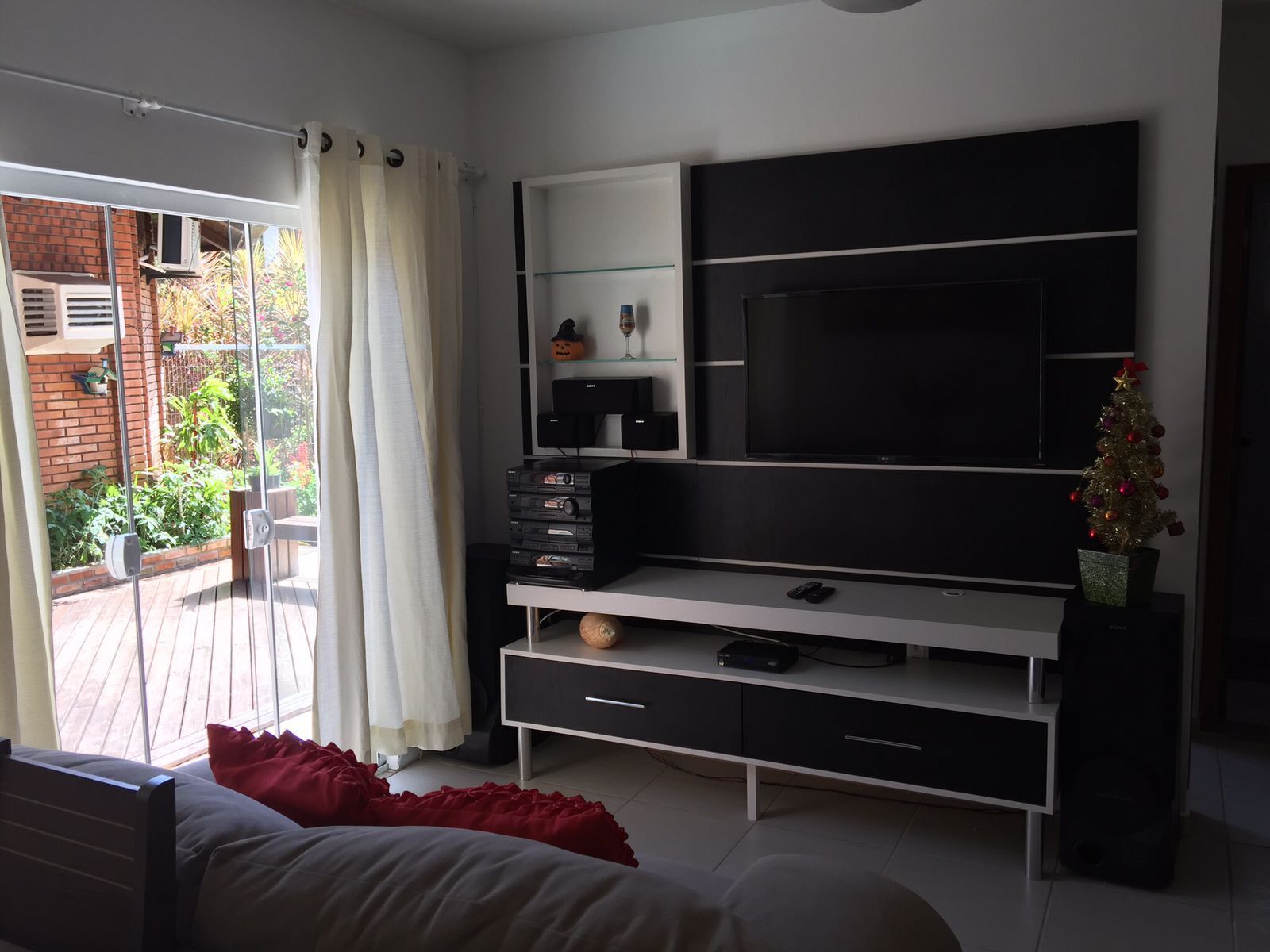 Et moderne soveværelse med et stort fjernsyn, et lille juletræ og en skydedør til en balkon.