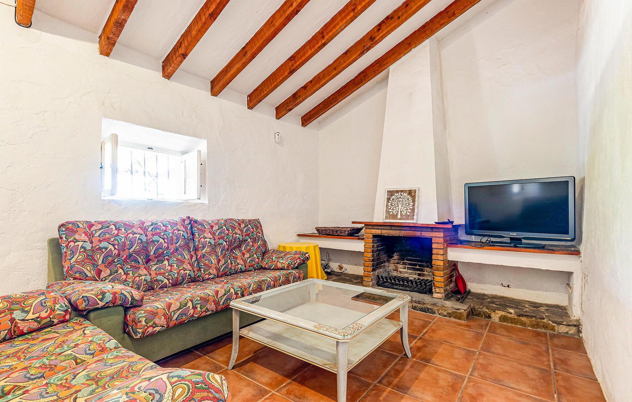 A living room with a sofa, a coffee table, a television, and a fireplace.