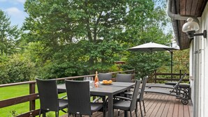 A wooden deck with outdoor furniture, including a table and chairs, and a bottle of champagne. - Pet friendly home in Tisvildeleje (Tisvildeleje)