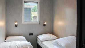 A small, single-room hotel room with two beds, a window, and two wall-mounted lights. - 3 bedroom lovely home in Epe (Epe)