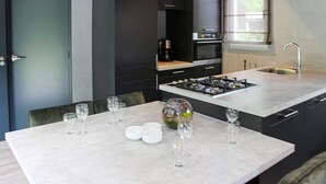 A modern kitchen with a central island, dark cabinetry, and a window providing natural light. - 3 bedroom lovely home in Epe (Epe)