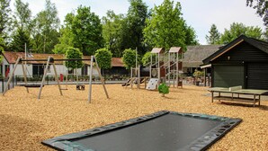 A playground with swings, slides, and a trampoline on a wooden deck. - 3 bedroom lovely home in Epe (Epe)