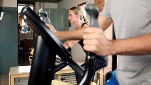 A person using an exercise bike in a room with a brick wall and a window.