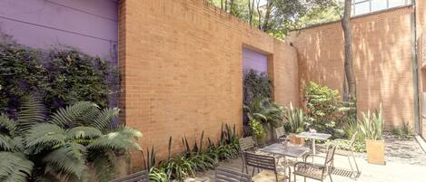 An outdoor patio with brick walls, a purple wall, and various plants.