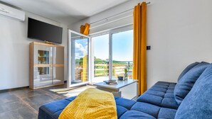 Un soggiorno moderno con un divano blu, una coperta gialla e una grande finestra con tende gialle.