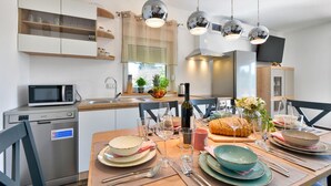 Una cucina moderna con un tavolo da pranzo apparecchiato, un forno a microonde, una macchina da caffè e un'ampia finestra con piante.