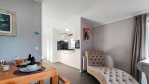 Un soggiorno moderno con zona pranzo, una poltrona capitonata e vista sulla cucina.