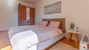Une chambre à coucher comprenant un lit, une table de chevet, une petite table ronde, un radiateur et une armoire.