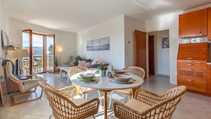 Un coin repas avec des chaises en osier, une table ronde et une vue sur l’extérieur.