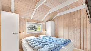 Ein Schlafzimmer mit einem Bett, einem Fenster und Holzwänden.