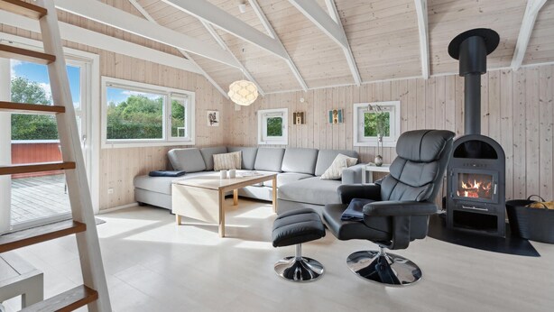 Ein gemütliches Blockhaus-Interieur mit einer Couch, einem Sessel und einem Kamin.