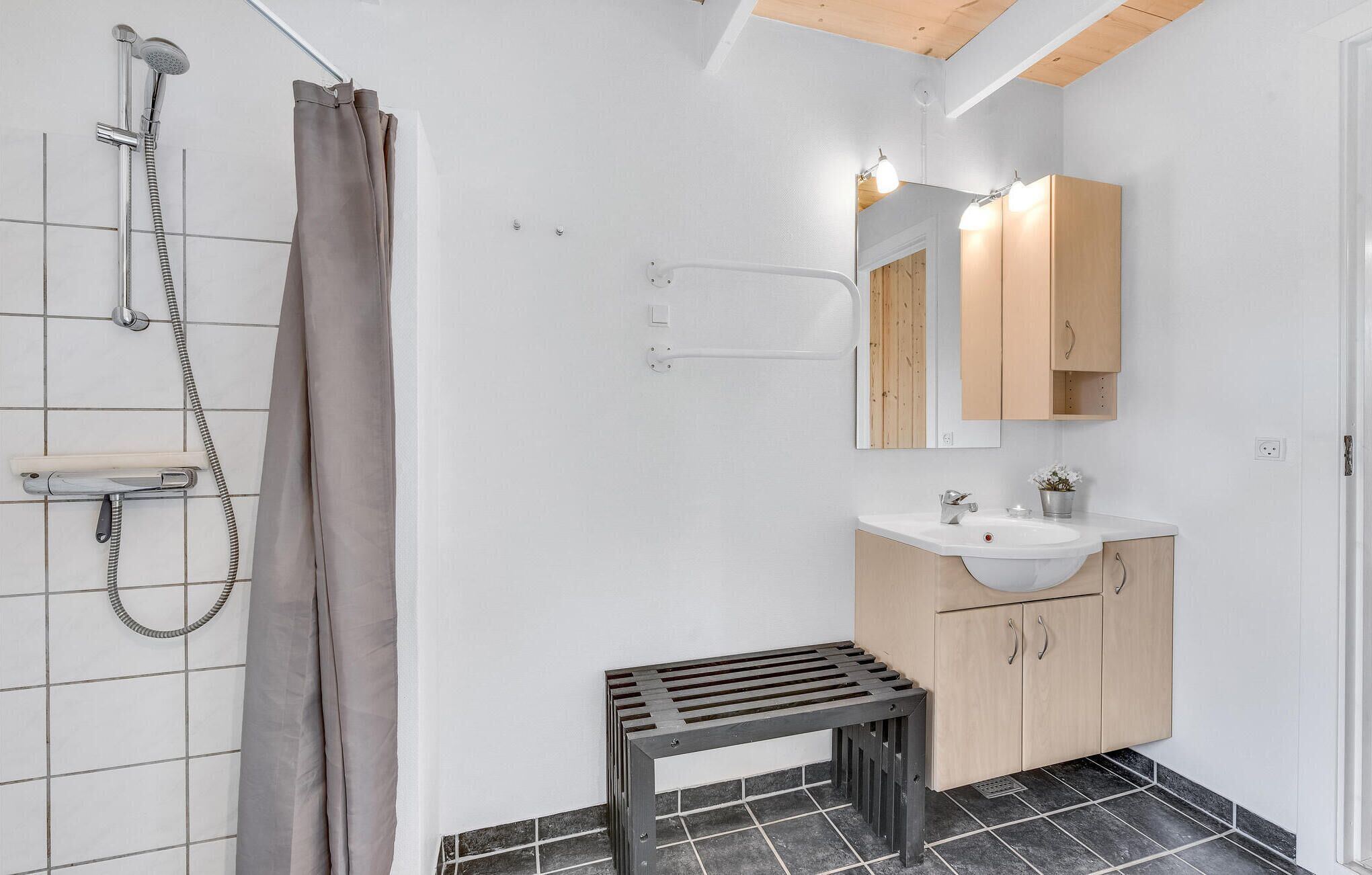 Baño con ducha, lavamanos y espejo.