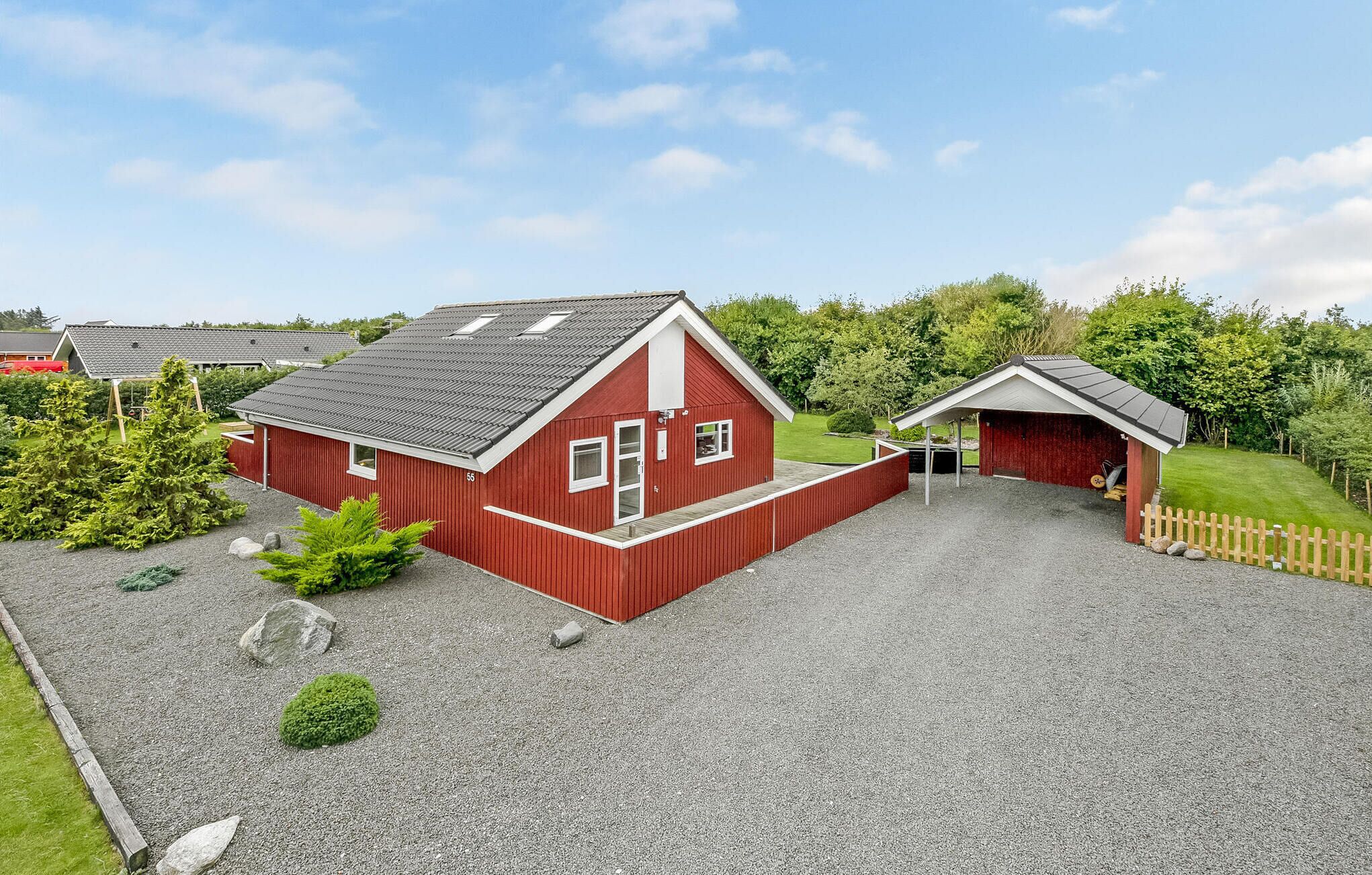 A red barn with a gravel driveway and a smaller adjacent structure.