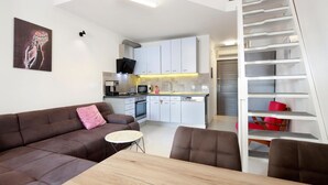 Een modern appartement met een zithoek, kitchenette en een ingebouwde boekenkast.