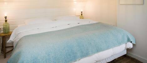 Un dormitorio con una cama, dos lámparas de noche y un cuadro en la pared.