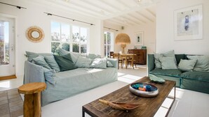 Ein geräumiges Wohnzimmer mit zwei Sofas, einem Holztisch und einem Essbereich mit Tisch und Stühlen.