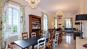 Un comedor con una mesa larga, sillas, una estantería y un sofá.