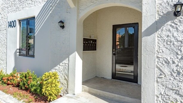 A building with a white stucco exterior, a black door, and a mailbox.